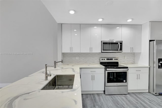 kitchen with white cabinetry, light stone counters, modern cabinets, and stainless steel appliances