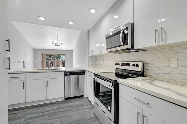 kitchen featuring a notable chandelier, a sink, appliances with stainless steel finishes, white cabinets, and decorative backsplash