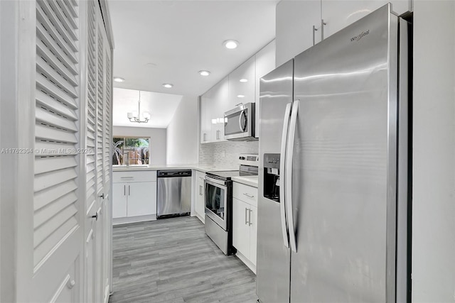 kitchen featuring tasteful backsplash, white cabinets, appliances with stainless steel finishes, and light countertops