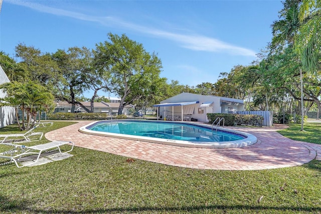 pool featuring a patio, fence, and a lawn