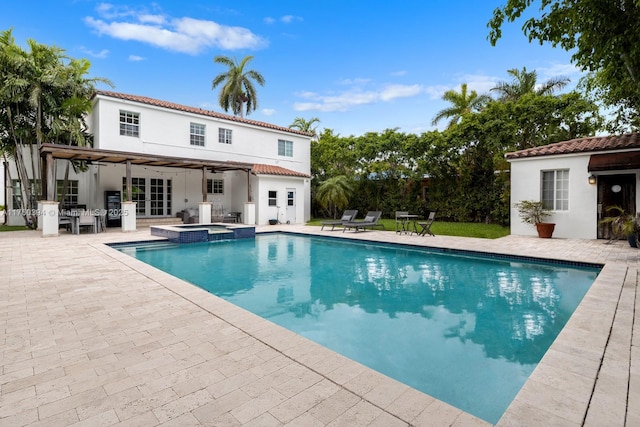 view of pool with a patio area, a pool with connected hot tub, and fence