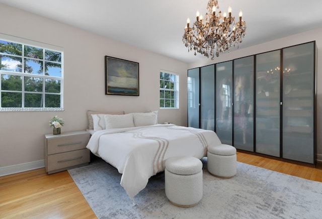 bedroom featuring a notable chandelier, wood finished floors, and baseboards