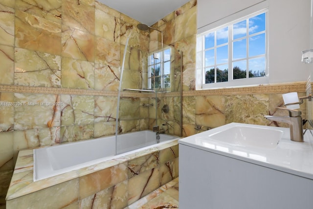 full bath featuring vanity, tile walls, and tiled shower / bath