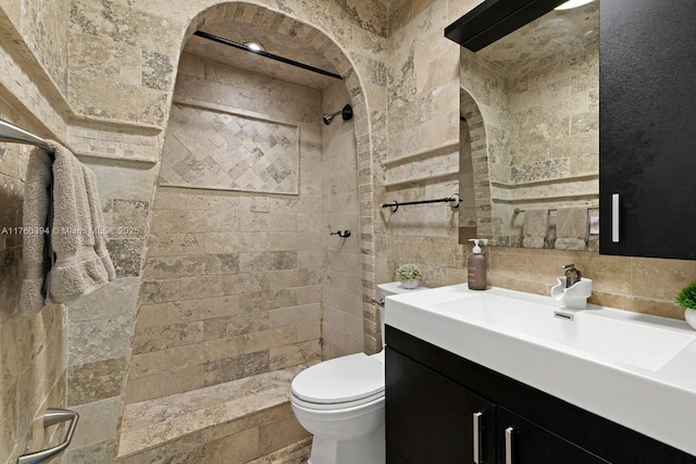 full bath with backsplash, tiled shower, toilet, and vanity