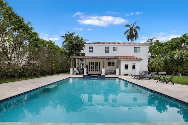 view of swimming pool with a pool with connected hot tub, a patio area, and french doors