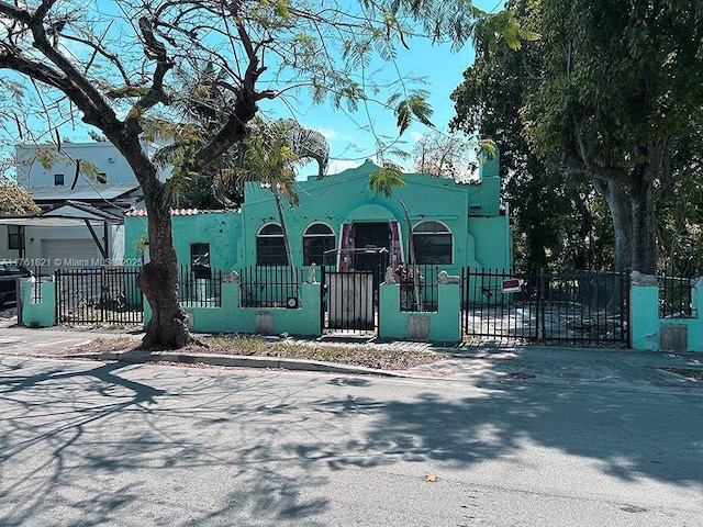 view of front of home with a fenced front yard, stucco siding, and a gate