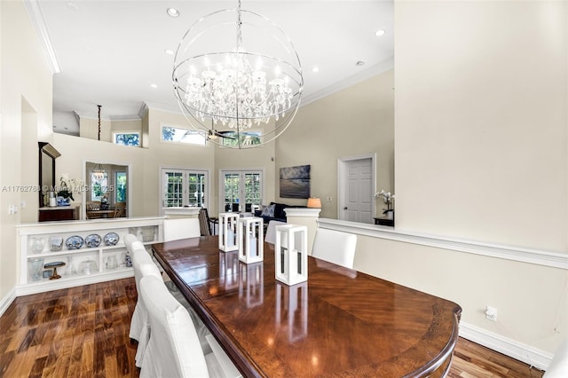 dining space with wood finished floors, french doors, a towering ceiling, crown molding, and a notable chandelier