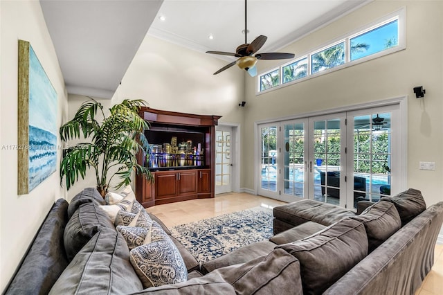 living area with a high ceiling, light tile patterned flooring, ornamental molding, ceiling fan, and french doors