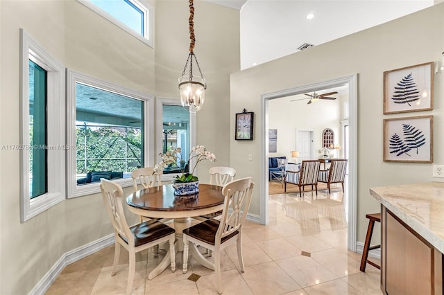 dining area with a high ceiling, light tile patterned floors, baseboards, and ceiling fan