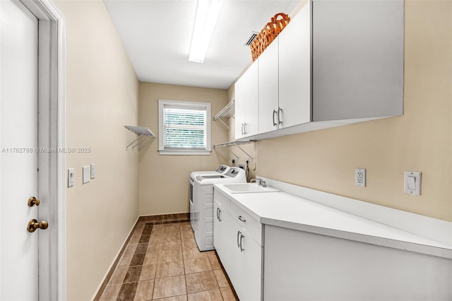 laundry room with baseboards, washing machine and dryer, light tile patterned floors, cabinet space, and a sink