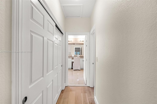 hallway with light wood-type flooring and a textured wall