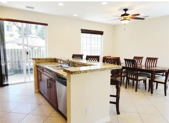 kitchen featuring visible vents, a sink, stainless steel dishwasher, a breakfast bar area, and light tile patterned floors