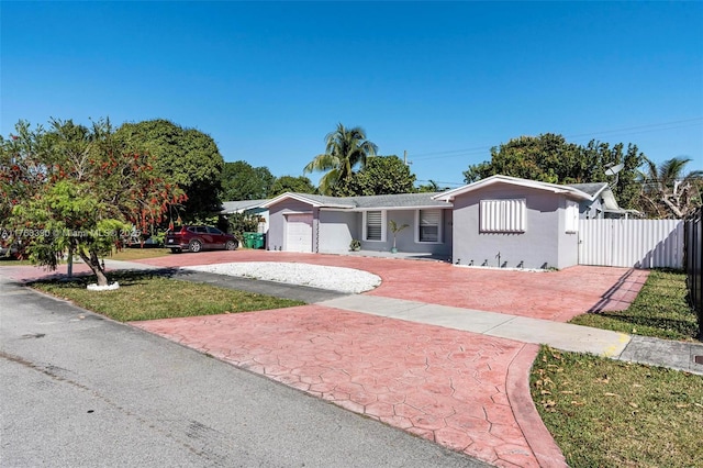 ranch-style house featuring stucco siding, decorative driveway, a garage, and fence