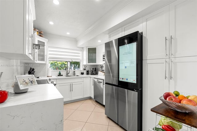 kitchen featuring light tile patterned floors, stainless steel appliances, ornamental molding, and white cabinetry