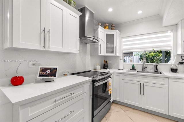 kitchen featuring crown molding, electric stove, light tile patterned flooring, white cabinets, and wall chimney exhaust hood