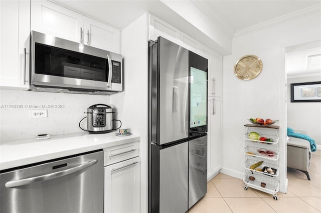 kitchen with crown molding, light countertops, light tile patterned floors, appliances with stainless steel finishes, and white cabinetry