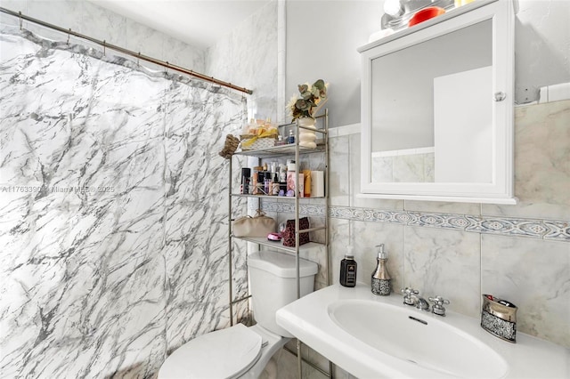 bathroom featuring a shower with shower curtain, tile walls, toilet, and a sink