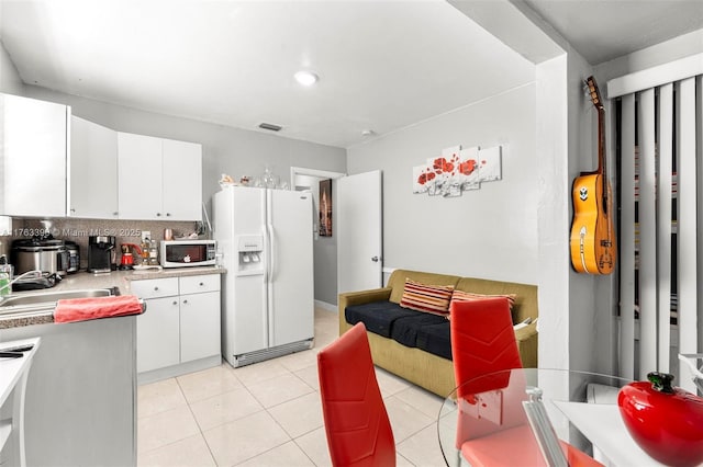 kitchen with white appliances, light tile patterned floors, visible vents, decorative backsplash, and light countertops