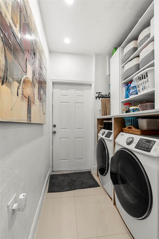 clothes washing area with tile patterned flooring, laundry area, washing machine and dryer, and baseboards