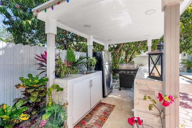 view of patio with an outdoor kitchen, fence, and a sink