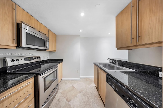 kitchen featuring a sink, recessed lighting, dark stone counters, appliances with stainless steel finishes, and baseboards