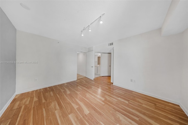 spare room with light wood-style flooring, rail lighting, baseboards, and visible vents