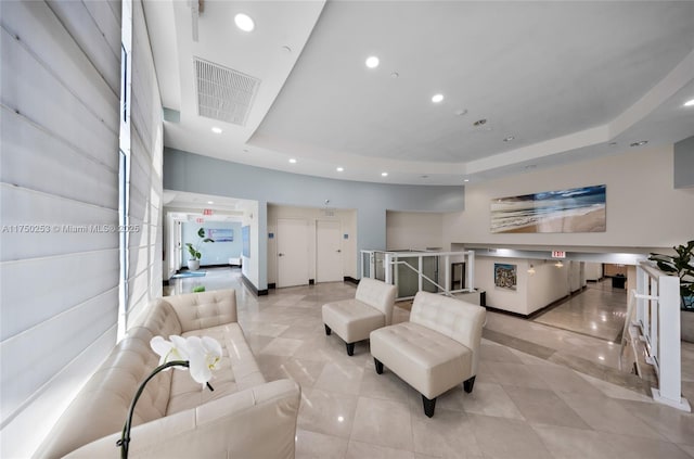 tiled living room with visible vents, recessed lighting, a raised ceiling, and baseboards