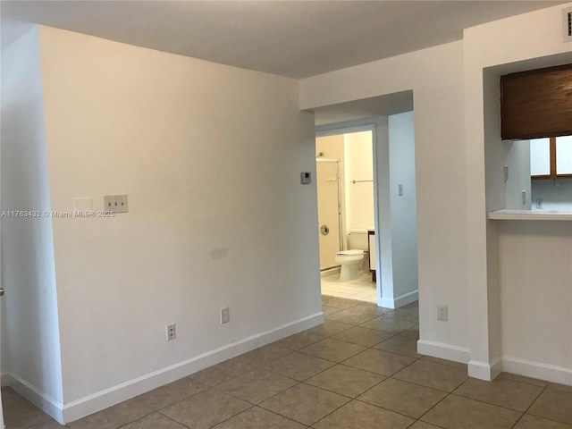 empty room with light tile patterned floors, visible vents, and baseboards