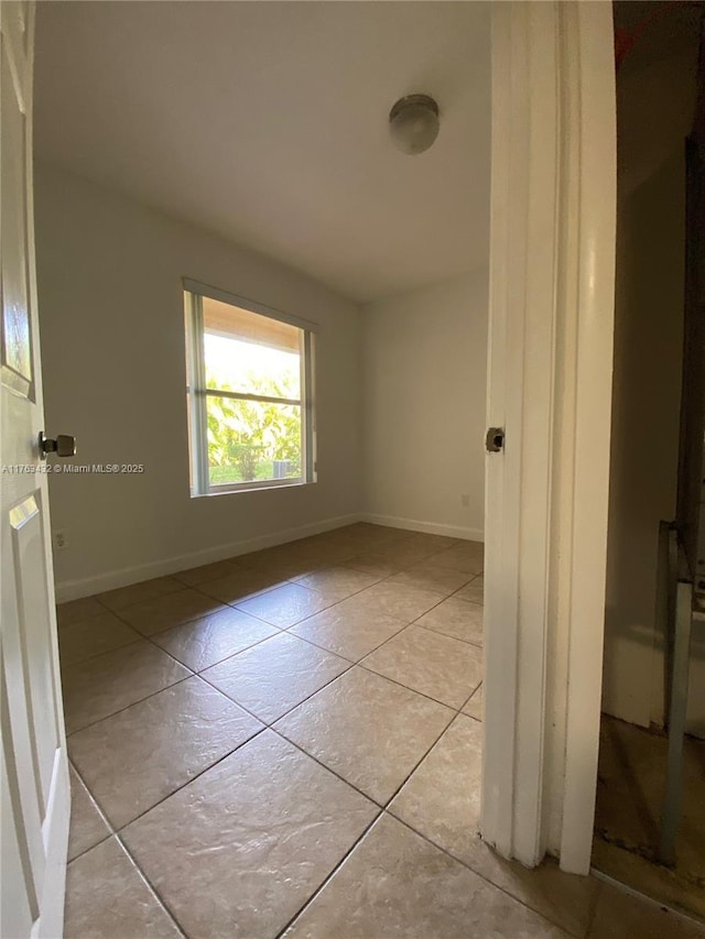 spare room featuring baseboards and light tile patterned flooring