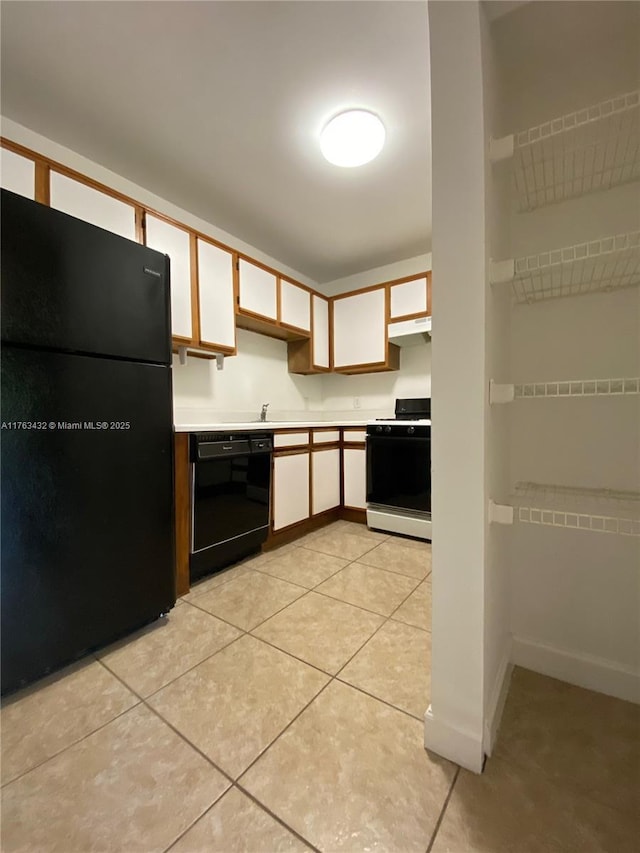 kitchen with black appliances, under cabinet range hood, white cabinets, light countertops, and light tile patterned floors