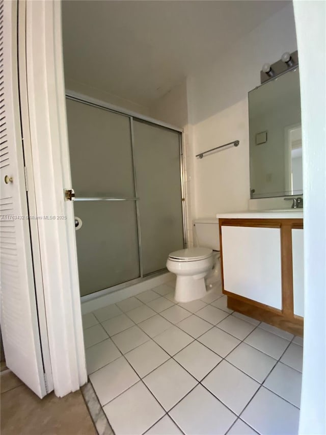 bathroom featuring tile patterned floors, toilet, a stall shower, and vanity