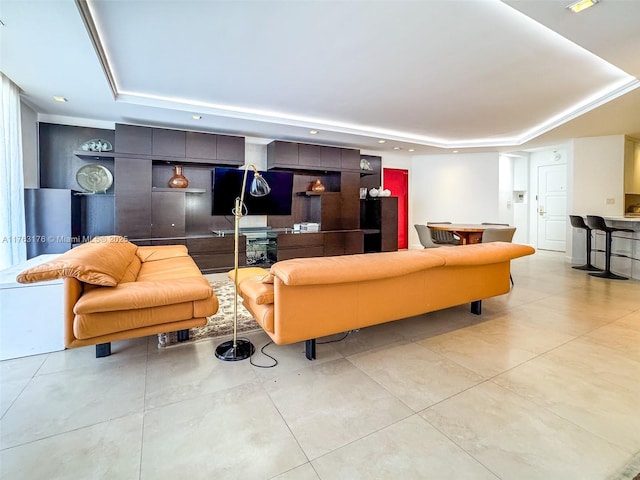 living room featuring a raised ceiling, light tile patterned floors, and recessed lighting