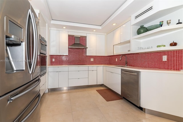 kitchen with a sink, modern cabinets, stainless steel appliances, wall chimney range hood, and white cabinets