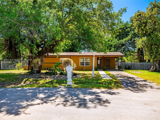 view of front of house featuring a front yard, a carport, driveway, and fence