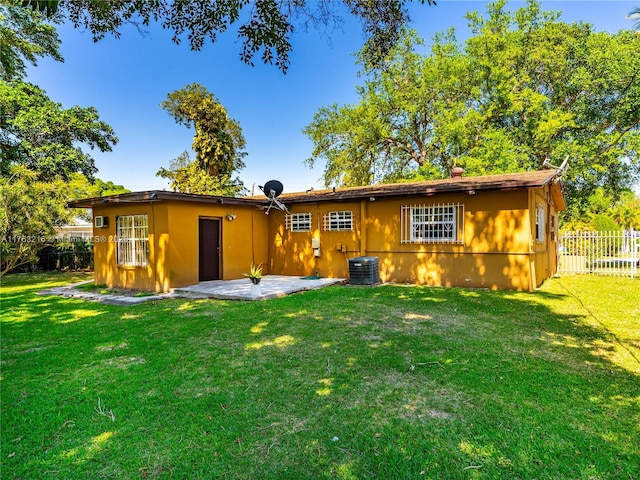 back of property with a patio area, central air condition unit, a yard, and fence