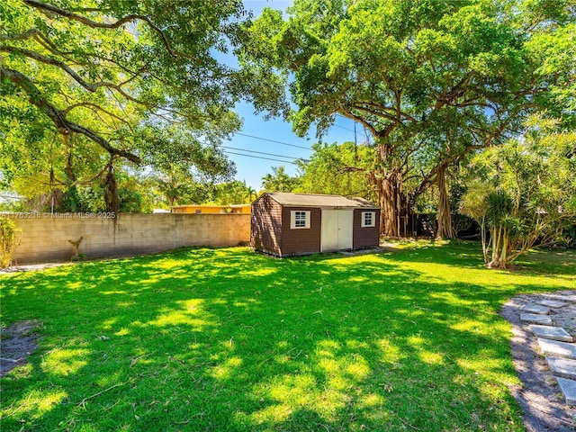 view of yard featuring an outdoor structure, a fenced backyard, and a shed