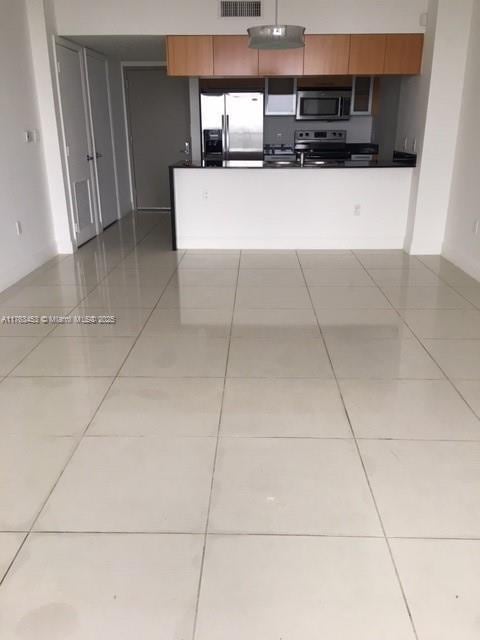 kitchen with tile patterned floors, dark countertops, visible vents, and appliances with stainless steel finishes