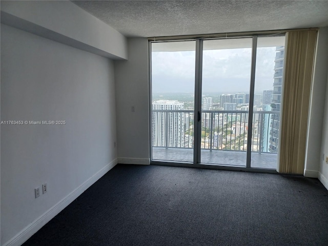 unfurnished room featuring a wall of windows, baseboards, plenty of natural light, a textured ceiling, and dark colored carpet