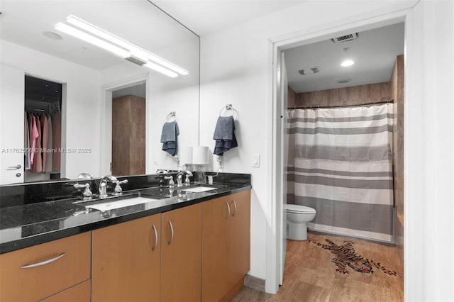 bathroom with a sink, visible vents, toilet, and double vanity