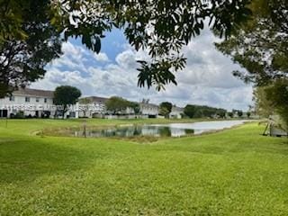 view of property's community with a lawn and a water view