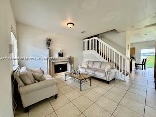 living area with tile patterned floors, a fireplace, and stairs