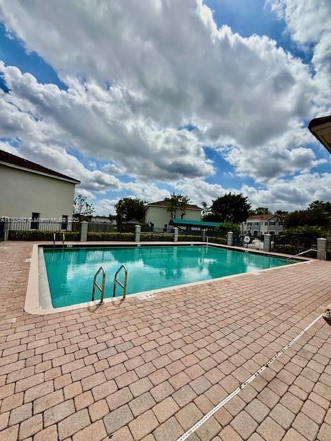 community pool with a patio and fence