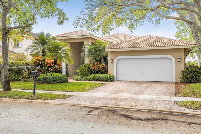 mediterranean / spanish home featuring stucco siding, a tiled roof, and decorative driveway