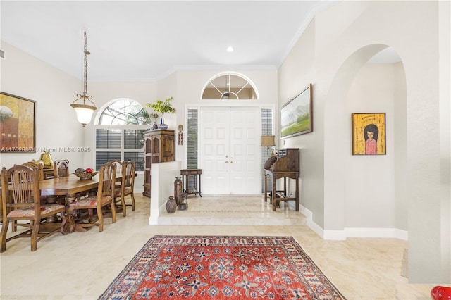 entryway with baseboards, arched walkways, and crown molding