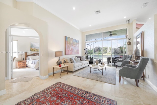 living area with ceiling fan, arched walkways, visible vents, and ornamental molding