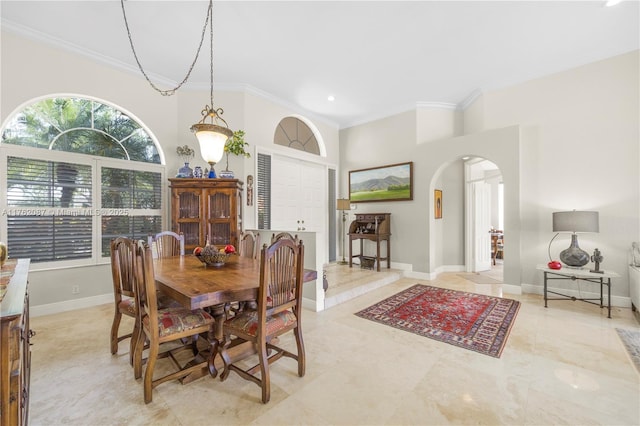 dining area with baseboards, arched walkways, and crown molding