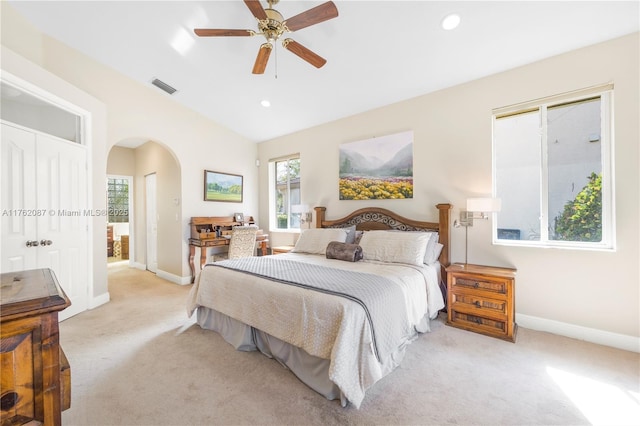 bedroom with arched walkways, visible vents, light colored carpet, and baseboards