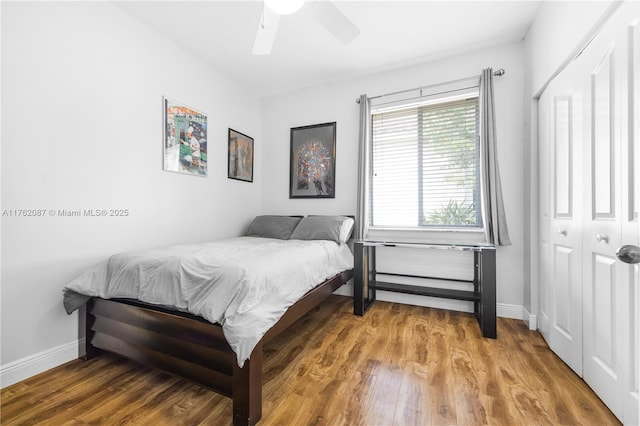 bedroom featuring a closet, baseboards, wood finished floors, and a ceiling fan