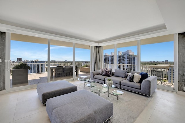 living room with tile patterned floors, a city view, floor to ceiling windows, and a raised ceiling