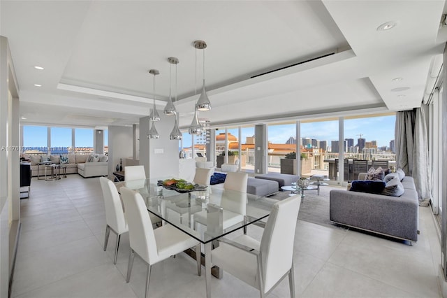 dining area with a city view, a raised ceiling, recessed lighting, and an inviting chandelier